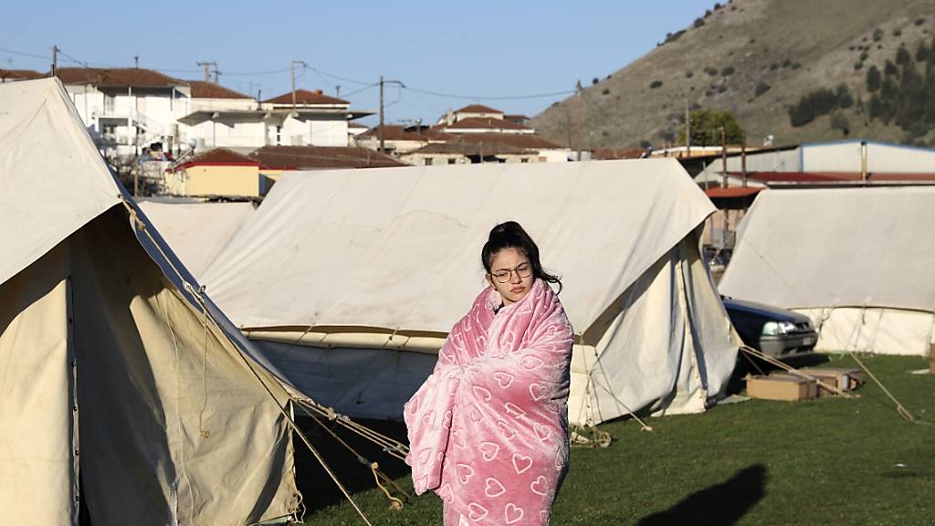 Ein Mädchen steht in eine Decke gehüllt vor Zelten. Nach einem starken Erdbeben in Mittelgriechenland haben viele Menschen die Nacht zum heutigen Donnerstag in Zelten, Hotels und bei Freunden verbracht. Foto: Vaggelis Kousioras/AP/dpa