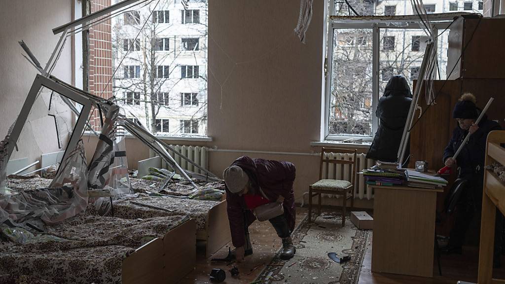 Frauen räumen nach einem russischen Raketenangriff auf ein Wohnviertel Glasscherben in einem Kindergarten weg. Foto: Evgeniy Maloletka/AP/dpa