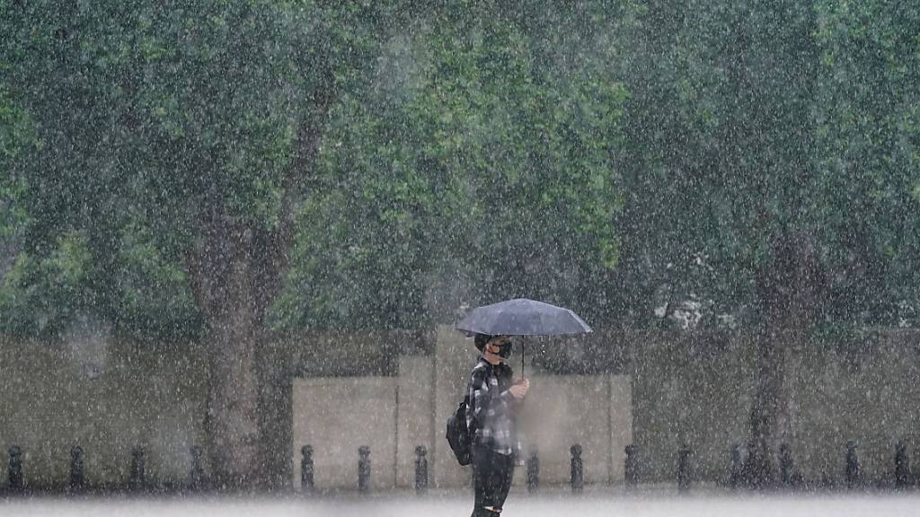 Eine Frau in London schützt sich mit einem Schirm vor dem starken Regen. Foto: Victoria Jones/PA Wire/dpa