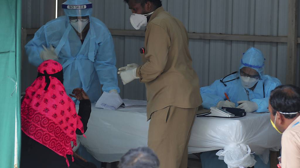 Ein indischer Arzt spricht mit einer Frau mit Covid-19-Symptomen in der Anmeldestelle des Krankenhauses «Government Fever Hospital». Foto: Mahesh Kumar A/AP/dpa
