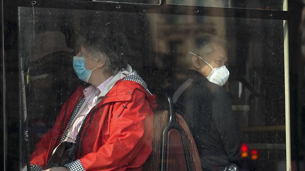 Menschen tragen Mund-Nasen-Schutz, während sie in einem Bus in London sitzen. Foto: Alberto Pezzali/AP/dpa