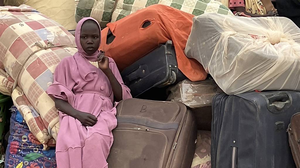 PRODUKTION - Eine junge Frau aus dem Sudan sitzt im Transitlager inmitten von Koffern, dem Hab und Gut der Flüchtlinge. Die Menschenrechtsorganisation Amnesty International hat ein Jahr nach Beginn des Konflikts im Sudan eine Kampagne für ein Waffenembargo gestartet. Foto: Eva-Maria Krafczyk/dpa