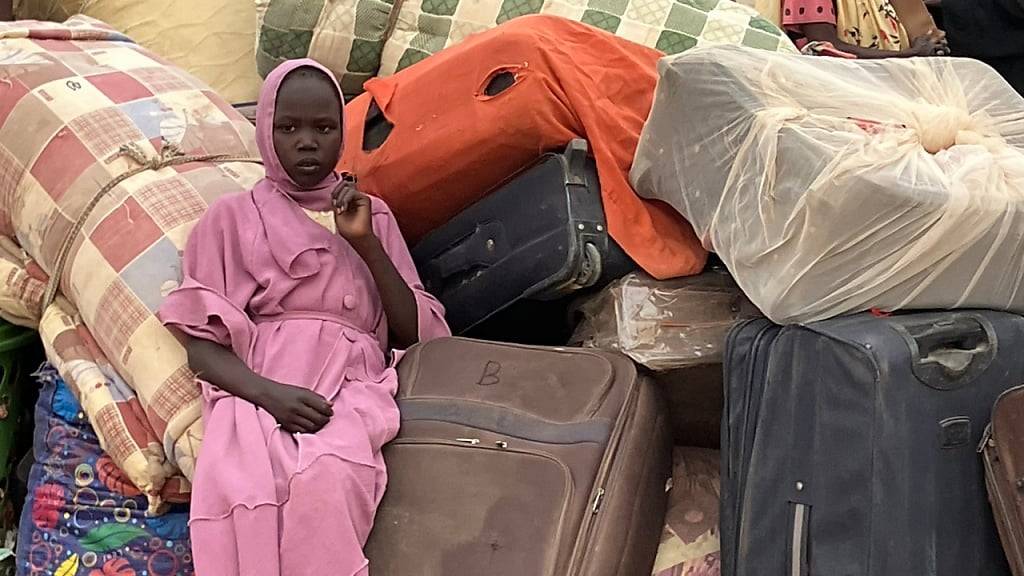 PRODUKTION - Eine junge Frau aus dem Sudan sitzt im Transitlager inmitten von Koffern, dem Hab und Gut der Flüchtlinge. Die Menschenrechtsorganisation Amnesty International hat ein Jahr nach Beginn des Konflikts im Sudan eine Kampagne für ein Waffenembargo gestartet. Foto: Eva-Maria Krafczyk/dpa