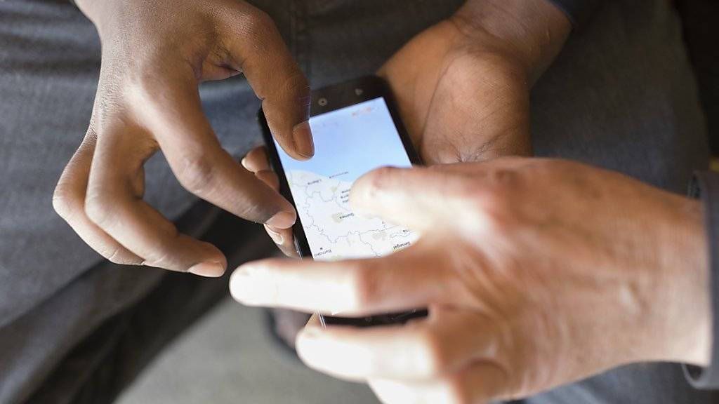 Ein Asylsuchender zeigt einem Betreuer auf einer Karte auf seinem Smartphone sein Heimatland. Bisher wurden in diesem Jahr so wenig Asylgesuche verzeichnet wie seit zehn Jahren nicht mehr. (Archivbild)
