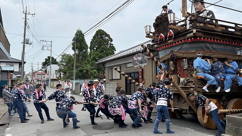 Auf massigen Holzrädern und begleitet von traditioneller Flöten- und Trommelmusik ziehen Hunderte Japanerinnen und Japaner beim Sawara Grand Festival, einem der größten Volksfeste der Kanto-Region um Tokio, mächtige Festwagen durch eine alte Handelsstadt gezogen. Foto: Lars Nicolaysen/dpa