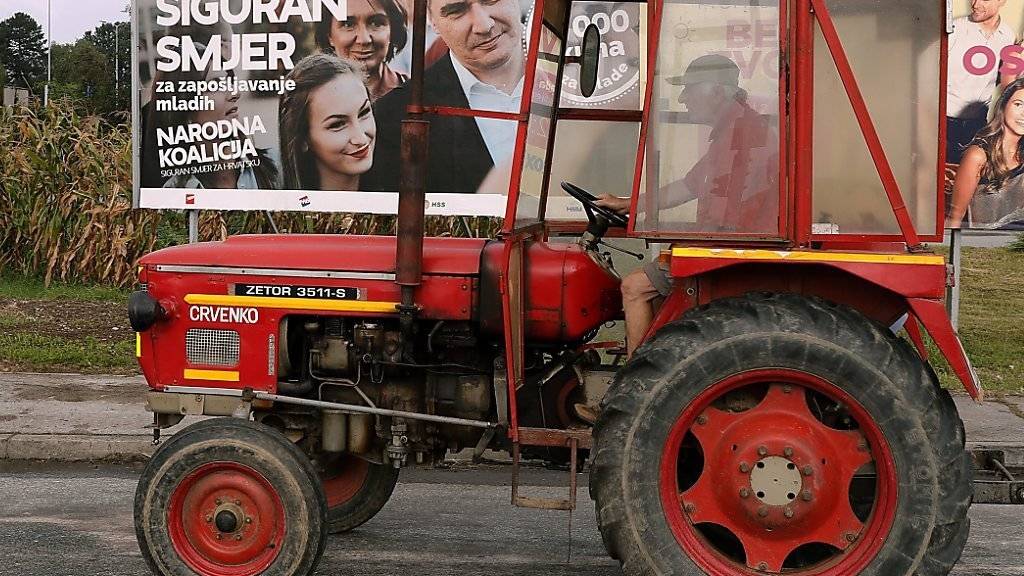 Ein Traktor fährt am Stadtrand von Zagreb an einem Wahlplakat vorbei.