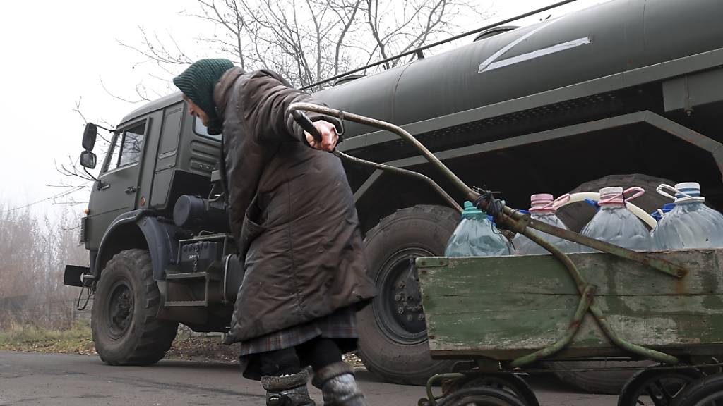 Ein älterer Zivilist zieht einen Wagen mit Flaschen mit frischem Wasser, die von der russischen Armee in der russisch kontrollierten Region verteilt wurden. Foto: Alexei Alexandrov/AP/dpa