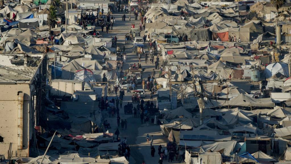 Palästinenser gehen durch ein behelfsmäßiges Zeltlager für Vertriebene in der Nähe des Hafens von Gaza-Stadt. Foto: Jehad Alshrafi/AP/dpa