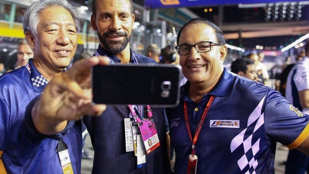 Rio Ferdinand (Mitte) macht in Singapur ein Selfie mit Premierminister Teo Chee Hean (l) und dem Minister für Handel und Industrie (r)