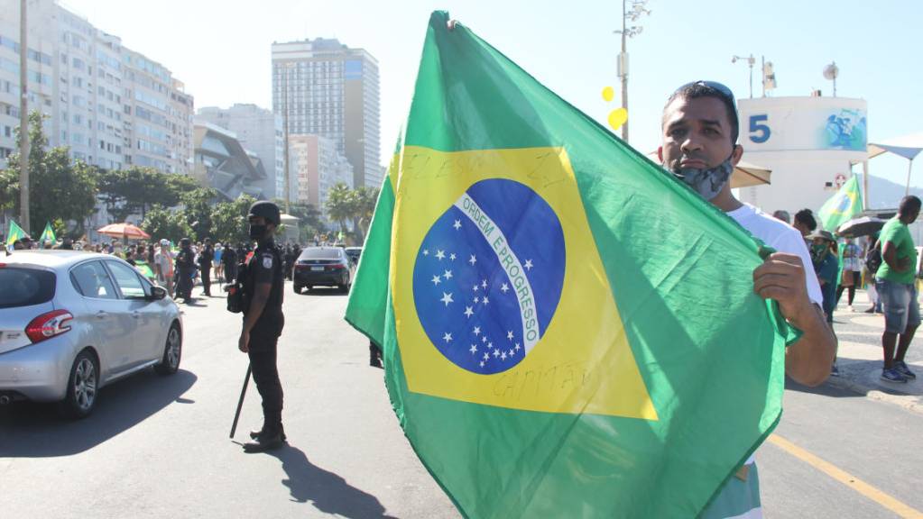 Ein Unterstützer des brasilianischen Präsidenten Bolsonaro hält bei einem Protest an der Copacabana eine brasilianische Fahne hoch. Foto: Fausto Maia/TheNEWS2 via ZUMA Wire/dpa