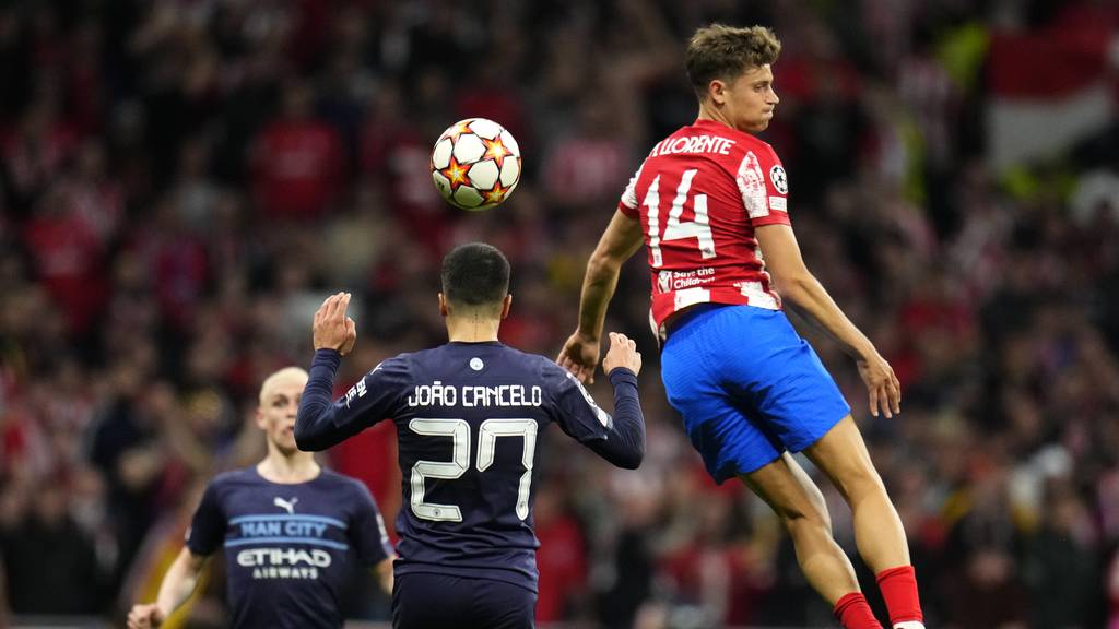 Atletico Madrid's Marcos Llorente, right, leaps up for a ball by Manchester City's Joao Cancelo, center, during the Champions League quarterfinal second leg soccer match between Atletico Madrid and Manchester City at Wanda Metropolitano stadium in Madrid, Spain, Wednesday, April 13, 2022.