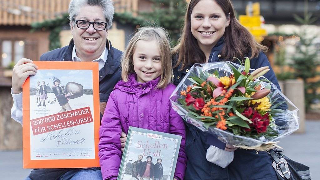 Der Kinobesuch hat sich gelohnt: Filmproduzent Peter Reichenbach (links) überreichte Nadine und Gabriela Holdener einen Blumenstrauss und ein Geschenk. Mutter und Tochter teilen sich den Preis für den 200'000sten Besucher von «Schellen-Ursli».