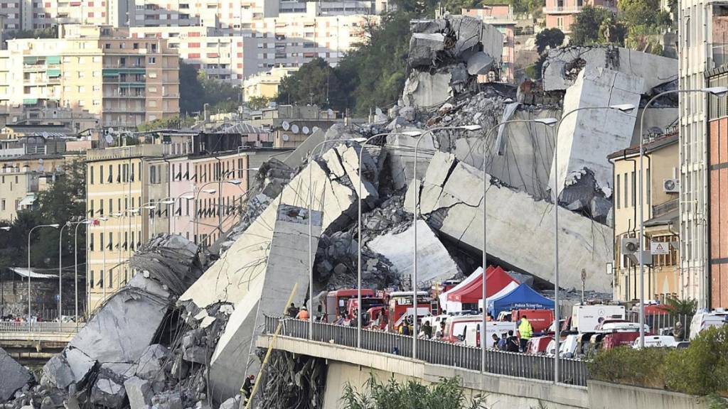 ARCHIV - Fahrzeuge der Rettungskräfte stehen vor der teilweise eingestürzten Autobahnbrücke. 2018 kamen beim Einsturz der «Ponte Morandi» auf etwa 100 Metern Länge 43 Menschen ums Leben. Foto: Luca Zennaro/ANSA/AP/dpa