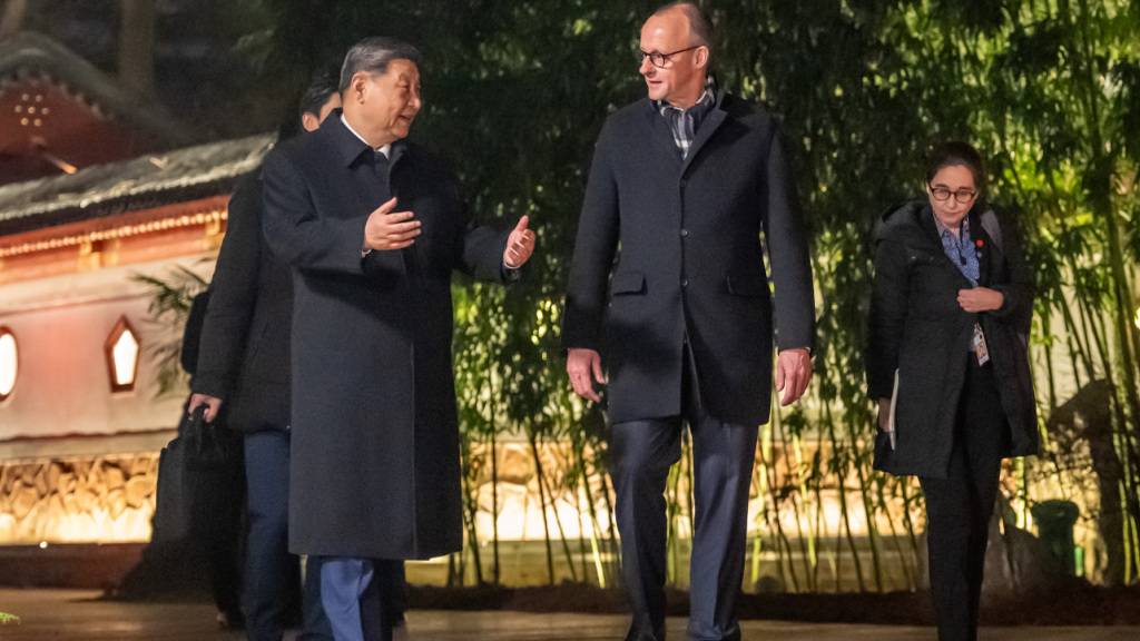 Bundeskanzler Friedrich Merz (CDU,M,r) geht neben Xi Jinping, Präsident von China im Staatsgästehaus und begleitet von Dolmetschern zu einem Abendessen. Foto: Michael Kappeler/dpa