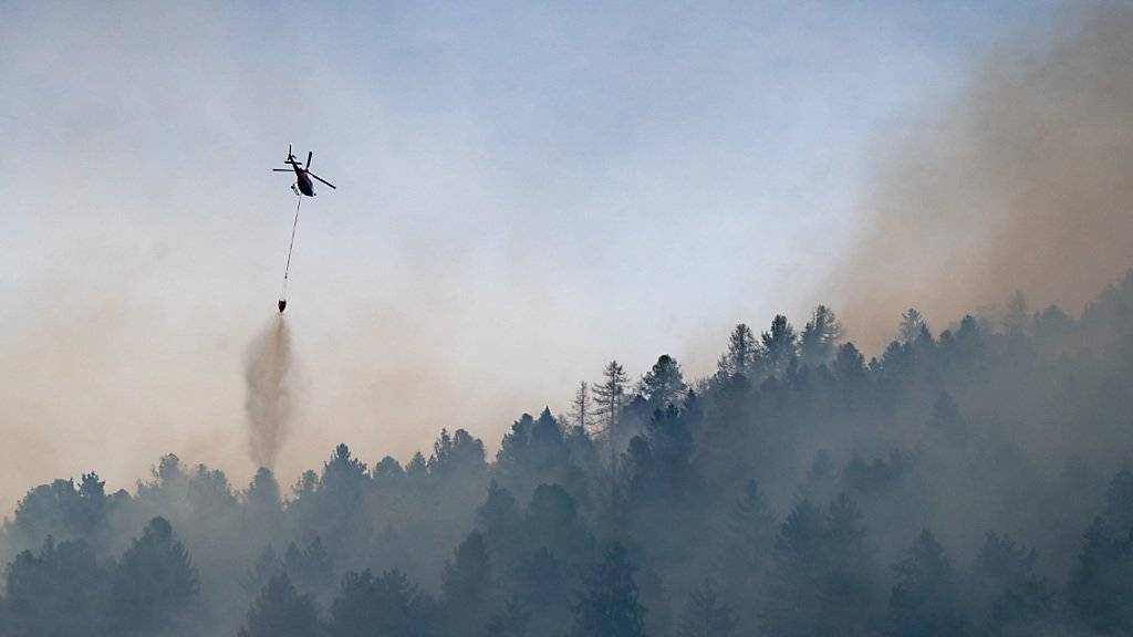Aus dem Wald bei Faido in der Tessiner Leventina steigen Rauchwolken. Ein Löschhelikopter ist im Einsatz.