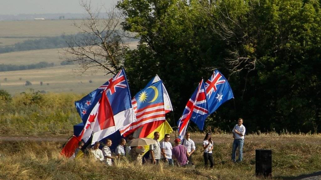 Teilnehmer einer Gedenkfeier in der Ostukraine halten Fahnen hoch von jenen Ländern, die beim Flugzeugabsturz Staatsbürger verloren haben.