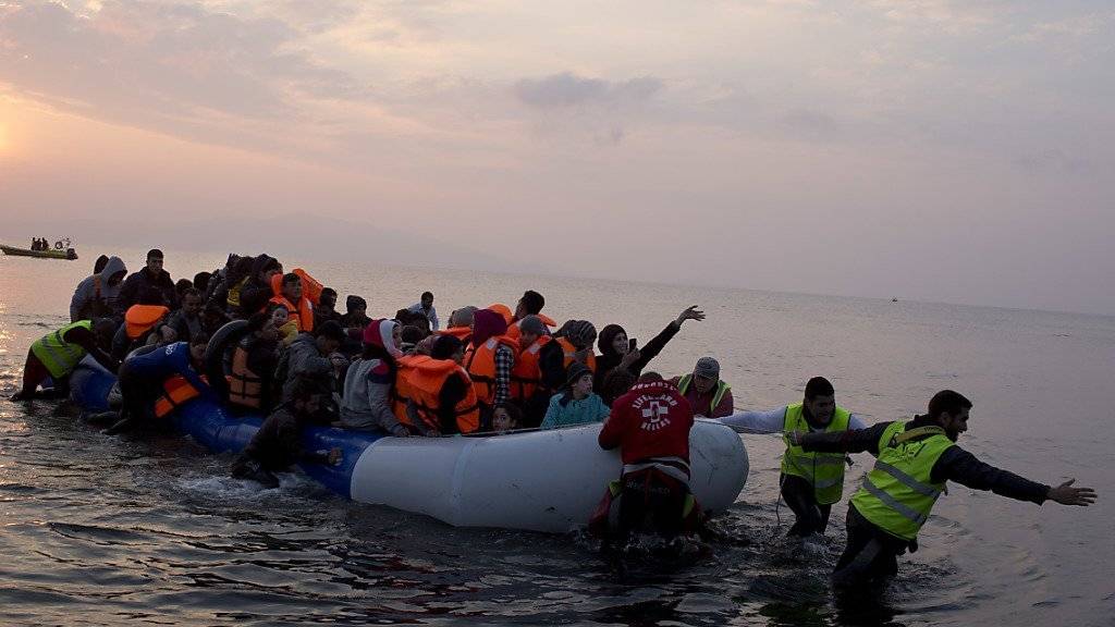 Freiwillige helfen Flüchtlingen in einem Schlauchboot an Land. (Archiv)