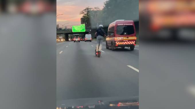 Mann fährt mit E-Scooter auf der Autobahn