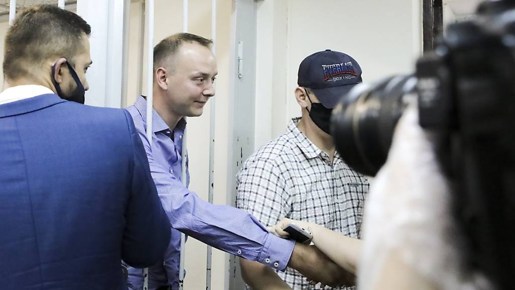 Iwan Safronow steht in einem Gerichtssaal in Moskau hinter Gittern und schüttelt einem Unterstützer die Hand. Foto: Sofia Sandurskaya/Moscow News Agency/AP/dpa