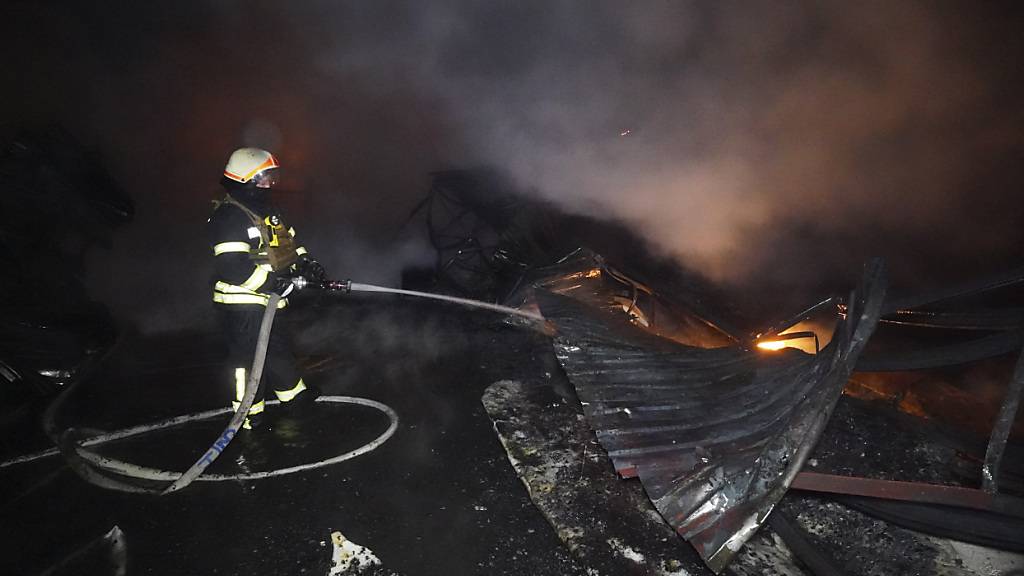 Feuerwehrleute löschen ein Feuer nach einem Treffer durch russischen Granatenbeschuss. Foto: Andrii Marienko/AP/dpa