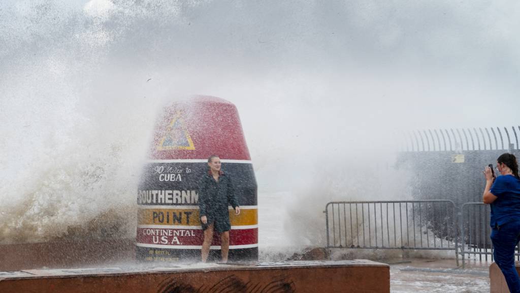 Besucher der Boje am Southernmost Point trotzen den vom Tropensturm «Idalia» verstärkten Wellen. Der Tropensturm «Idalia» hat sich im Golf von Mexiko zu einem Hurrikan entwickelt und wird laut Wetterexperten auf seinem Weg Richtung Florida weiter an Stärke gewinnen. Foto: Rob O'Neal/The Key West Citizen/AP/dpa
