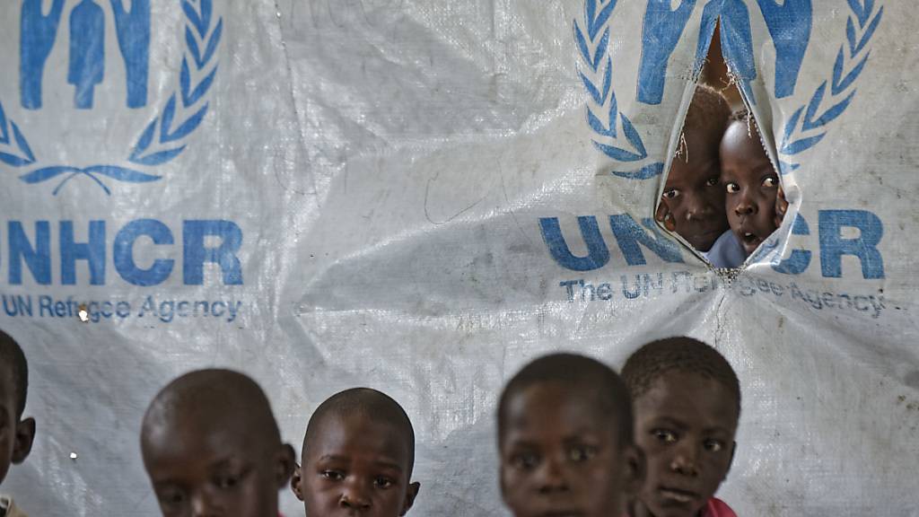 ARCHIV - Kinder schauen in der Ombechi Grundschule im Flüchtlingslager Bidi Bidi durch ein Loch in einem Zelt des Flüchtlingshilfswerkes UNHCR. Foto: Ben Curtis/AP/dpa