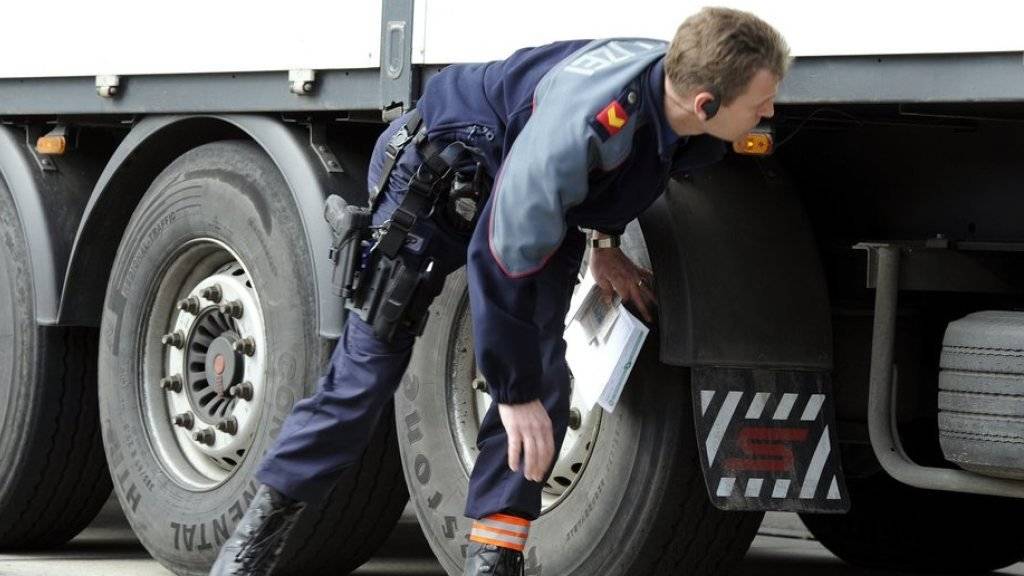 Ein Polizist kontrolliert einen Lastwagen anlässlich einer Car- und Schwerverkehrskontrolle der Kantonspolizei Zürich. (Archiv)