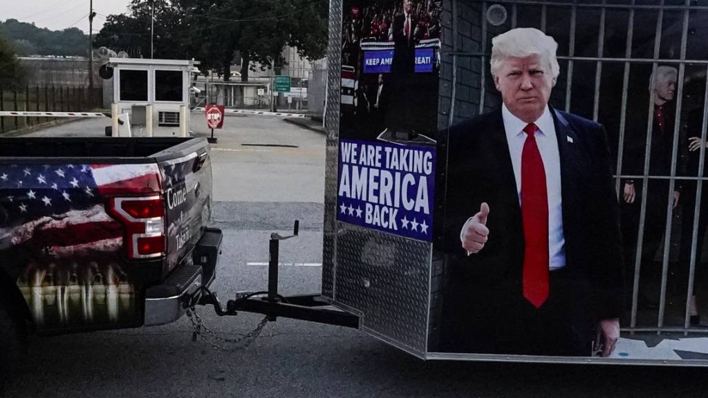 Ein Fahrzeug mit einem bedruckten Anhänger zur Unterstützung von Ex-US-Präsident Trump fährt am Gefängnis von Fulton County vorbei. Foto: Mike Stewart/AP/dpa