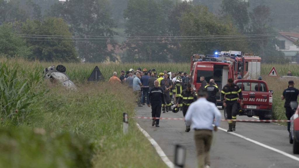 Feuerwehrleute arbeiten an der Unfallstelle, an der die Trümmer eines verbrannten Autos zu sehen sind. Foto: Matteo Secci/LaPresse/AP/dpa - ACHTUNG: Nur zur redaktionellen Verwendung und nur mit vollständiger Nennung des vorstehenden Credits