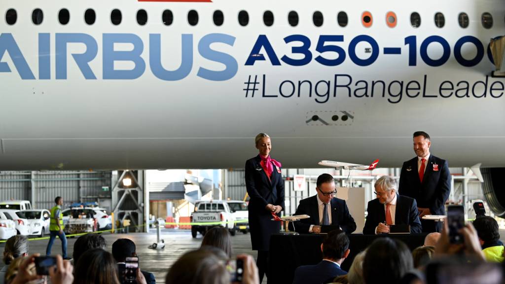 Qantas CEO Alan Joyce (middle left) and Airbus CEO Christian Scherer (middle right) sign an agreement at Sydney Domestic Airport, in Sydney, Monday, May 2, 2022. Qantas has confirmed an order for a dozen Airbus A350-1000 aircraft which will operate the worlds longest flights, connecting east-coast Australia to London and New York from late 2025. (AAP Image/Bianca De Marchi) NO ARCHIVING
