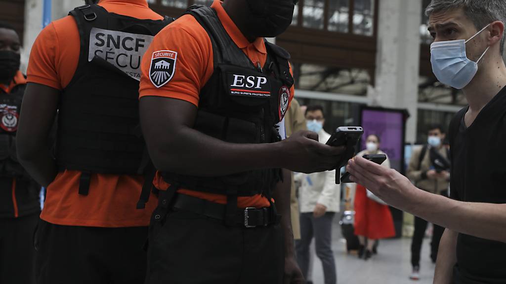ARCHIV - Sicherheitsbeamte kontrollieren in Lyon die Gesundheitspässe der Reisenden. Seit der Einführung der Nachweispflicht sind die Behörden in Frankreich auf 182.000 gefälschte Dokumente gestoßen. Foto: Adrienne Surprenant/AP/dpa