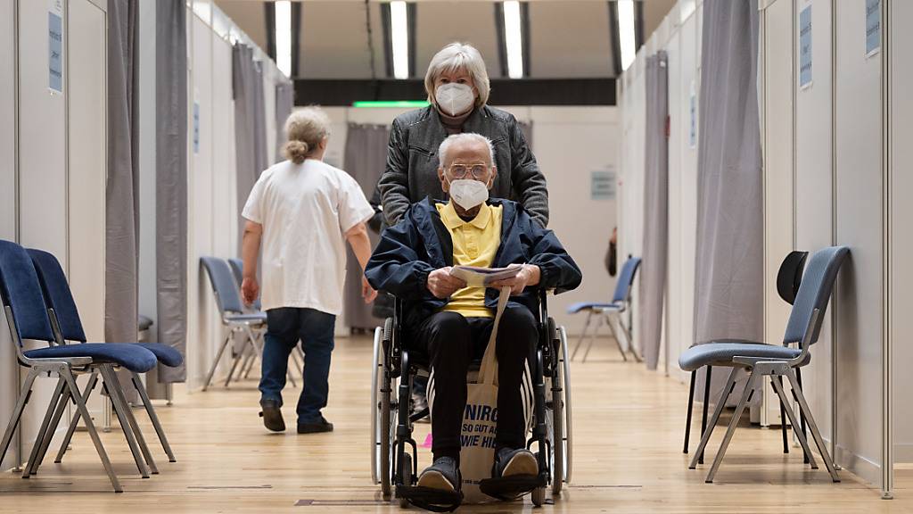 Ein Impfling wird nach seiner Impfung im Rollstuhl durch einen Gang des Impfzentrums des Klinikum Stuttgart geschoben. Foto: Marijan Murat/dpa