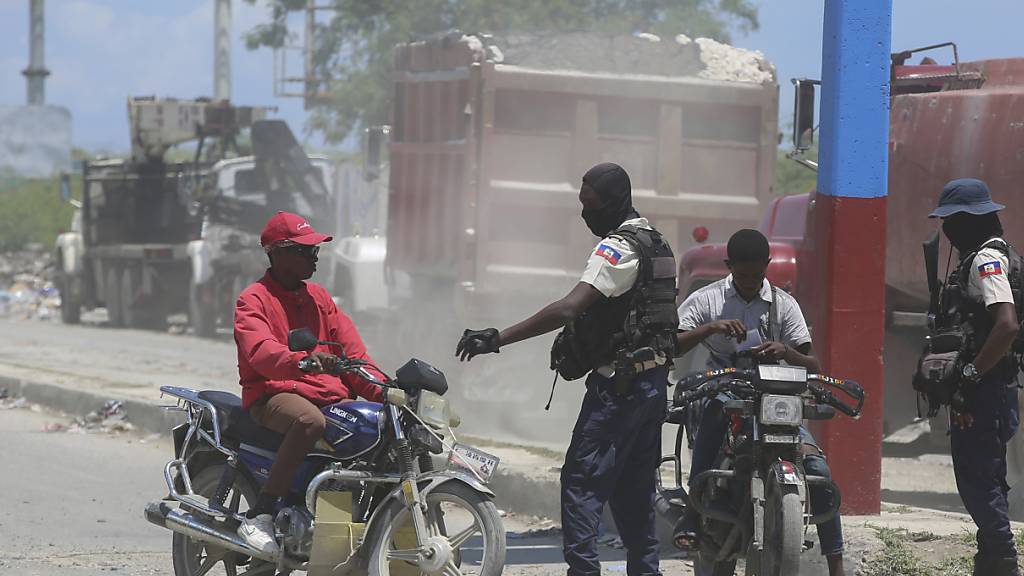 Die Polizei kontrolliert Motorradfahrer in der Nähe des Flughafens. Bei einem mutmaßlichen Bandenangriff auf US-Missionare in Haiti sind nach Angaben von deren Organisation drei Menschen getötet worden, darunter ein junges Paar. Foto: Odelyn Joseph/AP