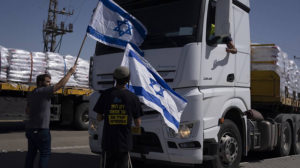 ARCHIV - Menschen mit israelischen Flaggen stehen vor Lastwagen mit humanitären Hilfsgütern, und versuchen sie an der Einfahrt in den Gazastreifen zu hindern. Foto: Leo Correa/AP/dpa
