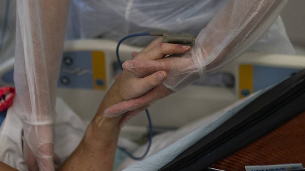Eine Krankenschwester hält die Hand eines Coronavirus-Patienten an einem Beatmungsgerät auf der Coronavirus-Intensivstation in einem Krankenhaus in Marseille. Foto: Daniel Cole/AP/dpa