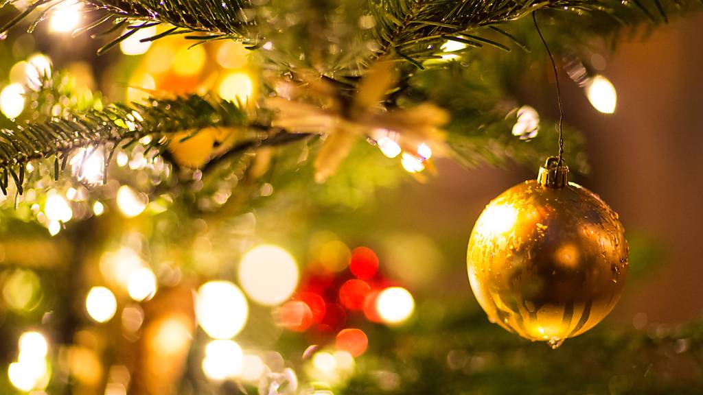 ARCHIV - Eine goldene Kugel hängt an einem Weihnachtsbaum. Foto: Friso Gentsch/dpa