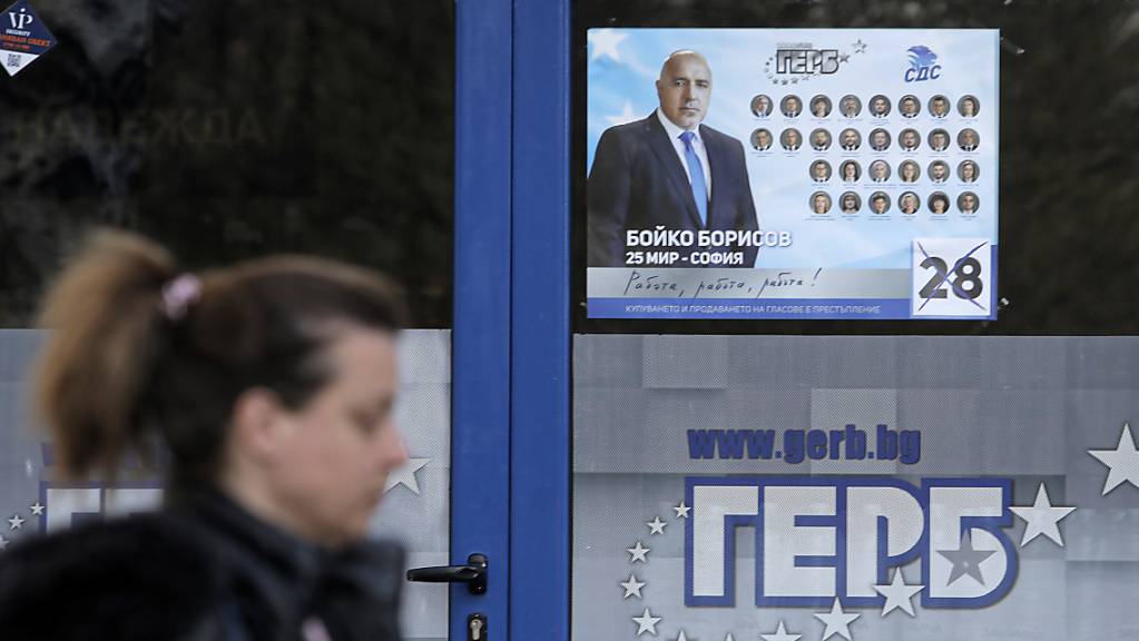 Eine Frau geht an einem Plakat vorbei, das den bulgarischen Premierminister Borissow zeigt. Foto: Valentina Petrova/AP/dpa