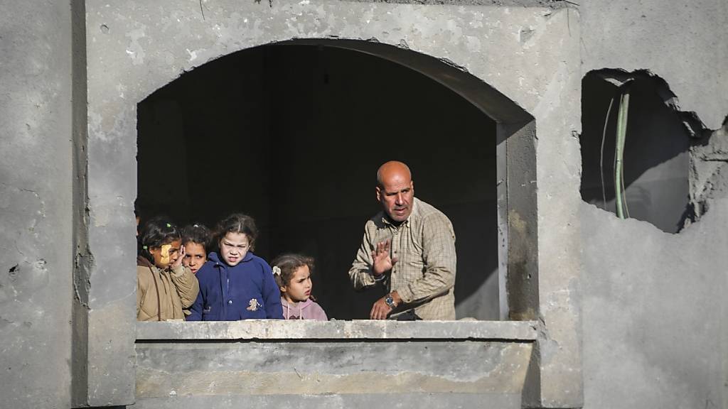 Menschen beobachten den Trauerzug für die Opfer eines israelischen Angriffs auf ein Haus am späten Samstag in Deir al-Balah, im zentralen Gazastreifen. Foto: Abdel Kareem Hana/AP/dpa