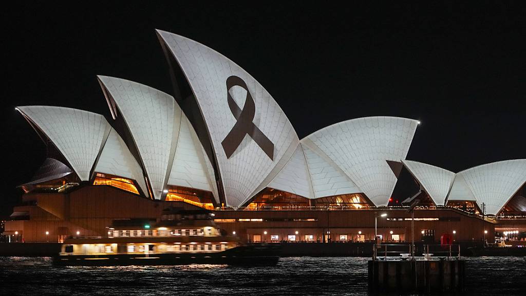 Das Opernhaus von Sydney wird im Rahmen eines nationalen Tages der Trauer nach dem tödlichen Messerangriff in einem Einkaufszentrum mit einer schwarzen Schleife angeleuchtet. In der australischen Metropole ist die Polizei am Montag erneut wegen eines Stich-Angriffs ausgerückt. Foto: Mark Baker/AP