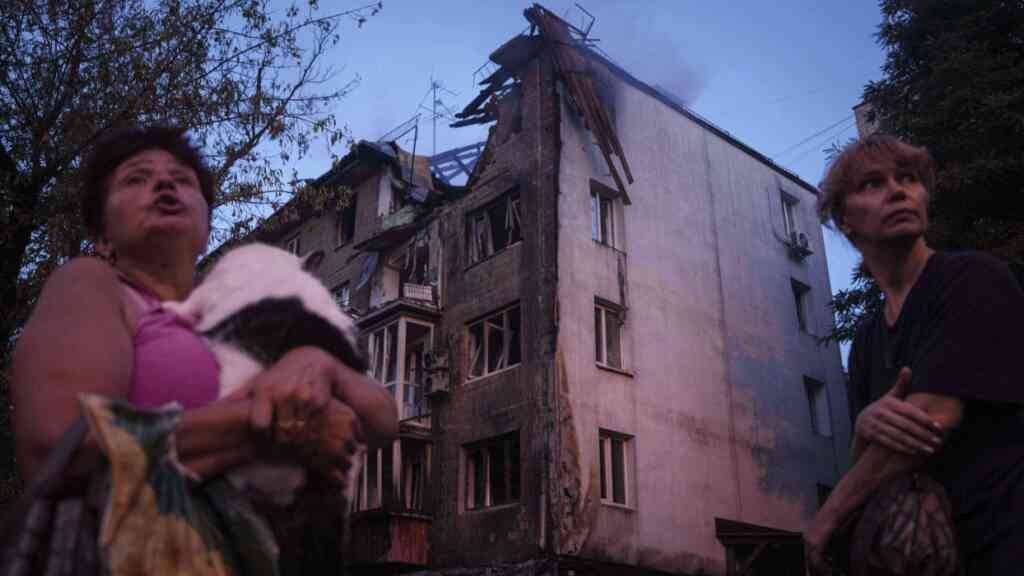 dpatopbilder - Anwohner stehen vor ihrem Haus, das durch einen russischen Angriff schwer beschädigt wurde. Foto: Evgeniy Maloletka/AP/dpa