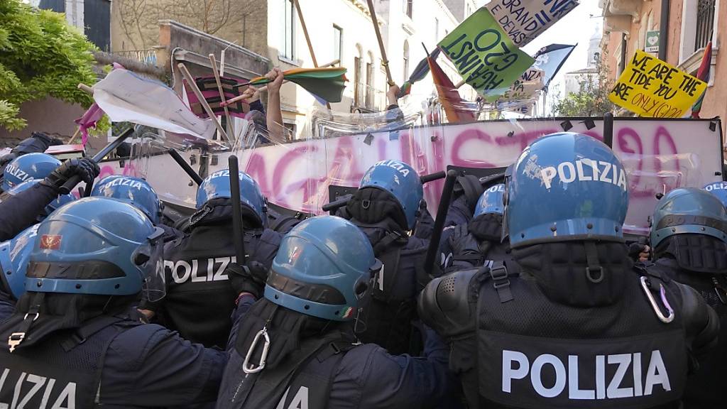 Demonstranten gegen den G20-Gipfel der Wirtschafts- und Finanzminister und italienische Polizisten stehen sich gegenüber. Foto: Luca Bruno/AP/dpa