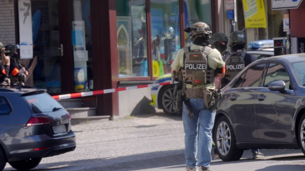 Polizisten stehen an einem Einsatzort. In einer Bankfiliale im rheinland-pfälzischen Sinzig ist es nach ersten Erkenntnissen der Polizei zu einer Geiselnahme gekommen. Die Einsatzkräfte sind mit einem Großaufgebot im Kreis Ahrweiler vor Ort. Foto: Thomas Frey/dpa