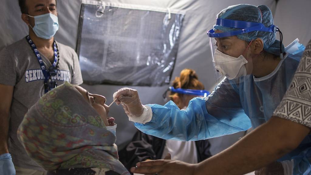 ARCHIV - Im Flüchtlingslager Moria wird einer Frau ein Abstrich aus dem Mund entnommen, um einen Corona-Test durchzuführen. Foto: Panagiotis Balaskas/AP/dpa