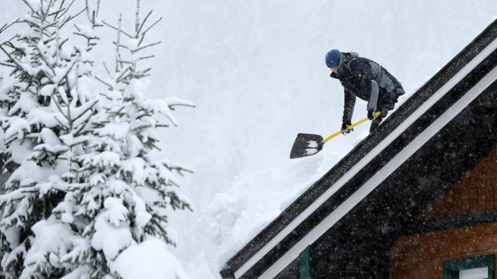 Ein Mann befreit ein Dach von der Schneelast am Mittwoch in der Nähe von Untertauern in Österreich.