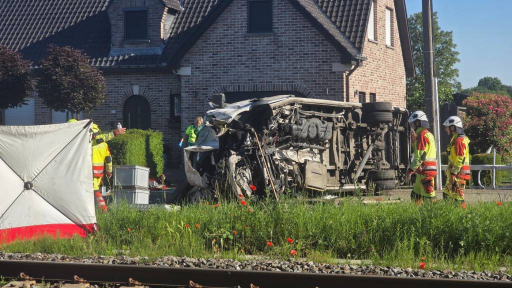 Rettungskräfte sind bei einem Unfallort im Einsatz, nachdem ein Zug mit einem Schulbus am Bahnübergang Vierhuizen in Buggenhout zusammengestoßen war. Foto: Koen Baten/AP/dpa