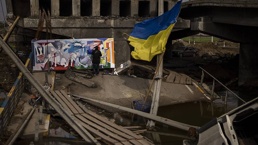 Roberto Marquez, ein in den USA lebender mexikanischer Künstler, malt auf einer zerstörten Brücke in Irpin bei Kiew ein Werk, das von Picassos Gemälde der am 26. April 1937 bombardierten baskischen Stadt Guernica inspiriert ist. Foto: Emilio Morenatti/AP/dpa
