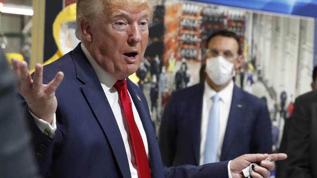 US-Präsident Donald Trump hat bei einem Besuch eine Fabrik in Michigan trotz Maskenpflicht erneut zumindest teilweise keine Schutzmaske getragen. Auf dem Bild hält er zwar eine Maske in der Hand, setzt sie aber nicht auf.