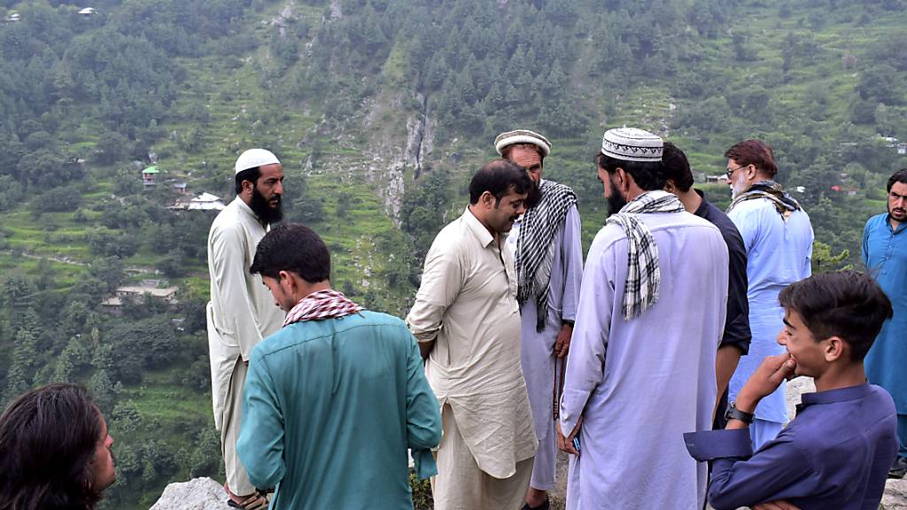 Anwohner und Journalisten versammeln sich in der Nähe des Unglücksortes in Pakistan. Foto: Saqib Manzoor/AP/dpa