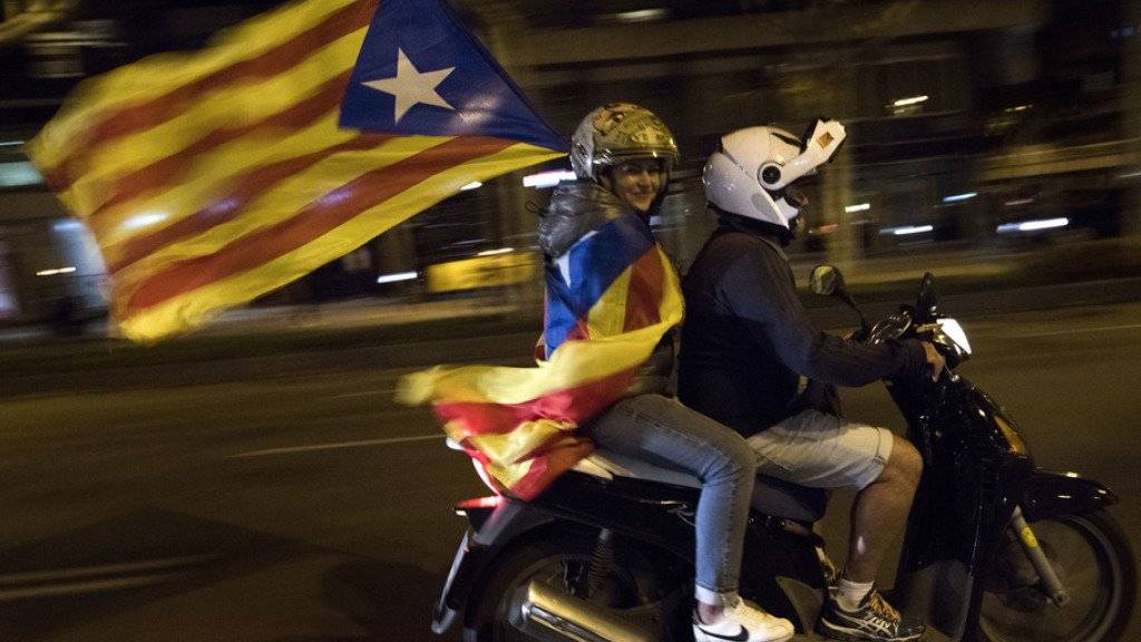 Eine Frau hält eine Flagge Kataloniens in den Händen. Der katalanische Regierungschef Puigdemont hat ein von der spanischen Zentralregierung gesetztes Ultimatum verstreichen lassen. Als Reaktion kündigt Madrid weitere Schritte zum Entzug der katalanischen Autonomie an. (Archiv)