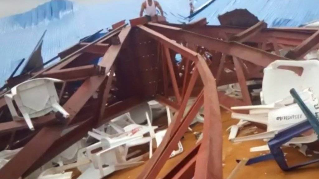 Einheimische nehmen eine eingestürzte Kirche in Uyo in Nigeria in Augenschein. Das Dach aus Metall war während eines Gottesdiensts über den Teilnehmern eingestürzt. Viele Menschen kamen dabei ums Leben.